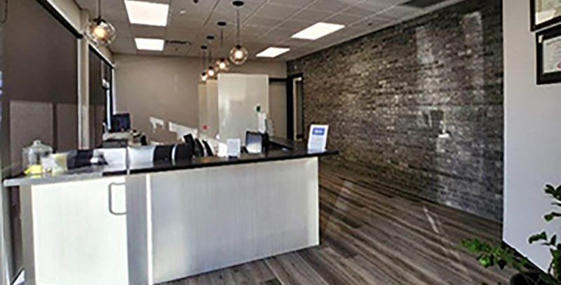 The image depicts a modern office reception area with a sleek, contemporary design featuring a wooden desk and a white countertop.
